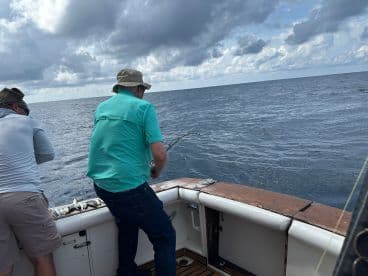 Two anglers actively reeling in their lines while fishing offshore, showcasing the excitement of deep-sea fishing.