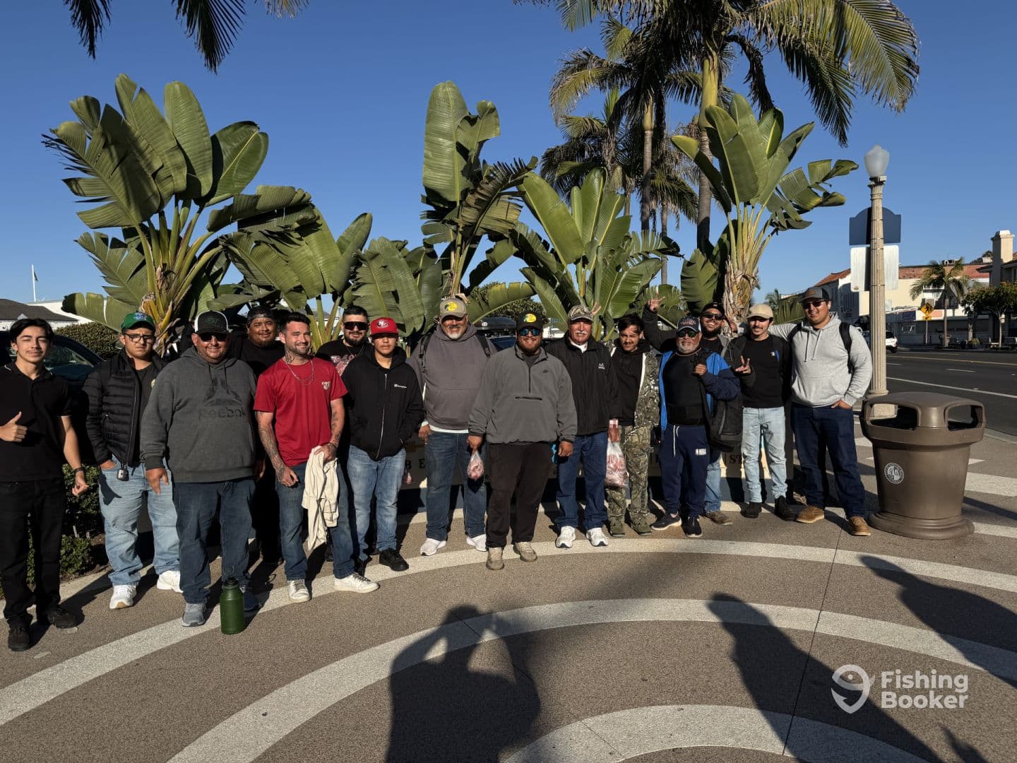 A group of anglers gathered at a scenic location, ready for a fishing adventure, with palm trees and a clear blue sky in the background.