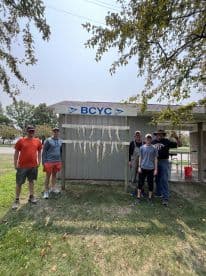 A group of anglers proudly displaying their catch of fish on a board at the BCYC, showcasing a successful fishing trip.