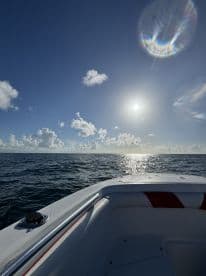A scenic view of the boat's exterior with the sun shining over the water, showcasing a beautiful day for fishing.