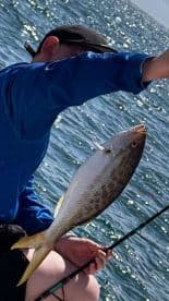 A young angler proudly displaying a freshly caught fish while fishing on a sunny day.