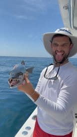 Angler displaying a Barracuda while having fun on a sunny day out on the water.
