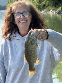 An angler proudly displaying a large Largemouth Bass while fishing in a serene lake setting.