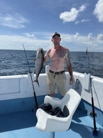 Angler proudly displaying a large fish on a fishing charter in open waters, showcasing a sunny day at sea.