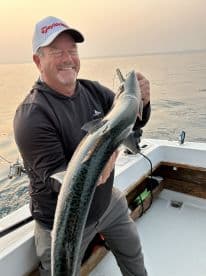 An angler proudly displaying a large fish while aboard a fishing boat, enjoying a serene day on the water.