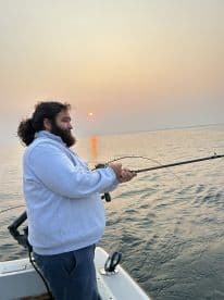 An angler casting a line during sunset on a tranquil fishing trip, showcasing the serene environment and the excitement of fishing.