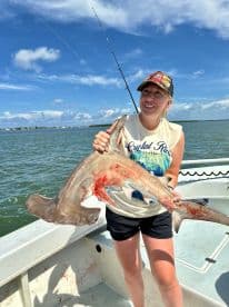 An angler proudly displaying a caught shark while fishing in a coastal waterway, showcasing the excitement of a successful fishing trip.