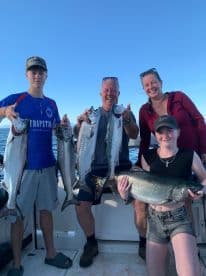 A family proudly displaying their catch of Salmon while enjoying a day out on the water.