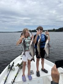 Two young anglers proudly displaying their catch of catfish while enjoying a day on the water.