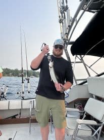 Angler proudly displaying a freshly caught trout while aboard a fishing boat, showcasing a successful day on the water.