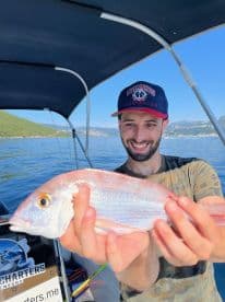 Angler proudly displaying a freshly caught Red Snapper while on a fishing charter in Montenegro.