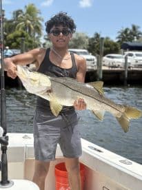 Young angler proudly holding a large Snook while on a fishing trip, showcasing the excitement of a successful catch.