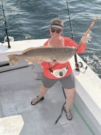 An angler proudly displaying a large Grouper caught while fishing offshore, showcasing a sunny day on the water.