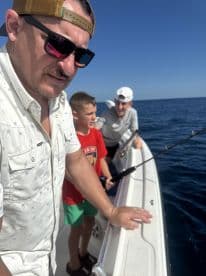 A group of anglers, including a young boy, engaged in fishing on a sunny day, showcasing the excitement of reeling in a catch.