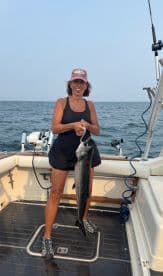 Angler proudly displaying a large fish on the deck of a boat, enjoying a day of fishing on the open water.