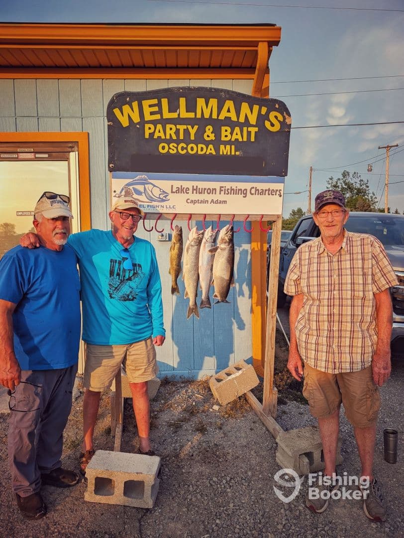 Three anglers proudly displaying their catch of Lake Huron fish on a board at Wellman's Party & Bait in Oscoda, MI.