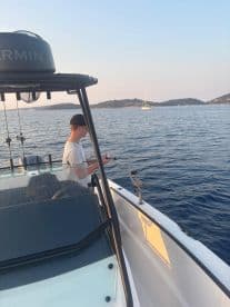 A young angler casting a line from a modern boat in a serene coastal setting, showcasing the excitement of fishing.