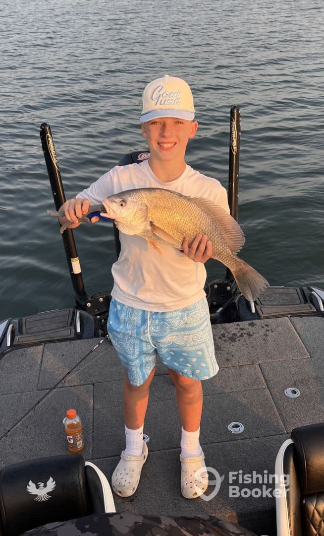 Young angler proudly displaying a large Snapper while fishing on a boat, showcasing a successful day on the water.