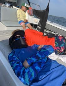 Two young anglers relaxing inside the boat, showcasing a comfortable seating area during a fishing trip.
