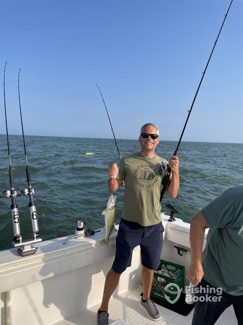 Angler proudly displaying a freshly caught fish while fishing on a boat in open waters.