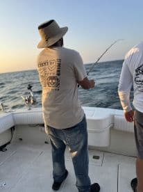 Angler casting a line while fishing on a boat during sunset, showcasing an engaging fishing experience.
