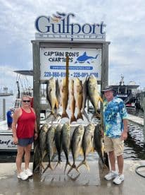 Two anglers proudly display a variety of fish, including Yellowtail and Snapper, on a catch board at Captain Ron's Charters in Gulfport, Mississippi.