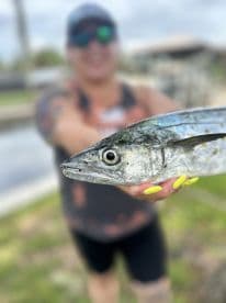 An angler proudly displaying a freshly caught fish with vibrant colors, set against a scenic backdrop of a fishing area.