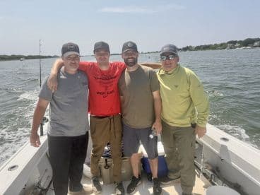 Group of four anglers enjoying a day on the water, showcasing camaraderie aboard a fishing boat.