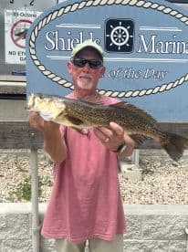 An angler proudly displaying a large Speckled Trout at Shields Marina, showcasing a successful day of fishing.