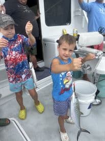 Two young anglers proudly displaying their catch of Spanish Mackerel aboard a fishing charter.