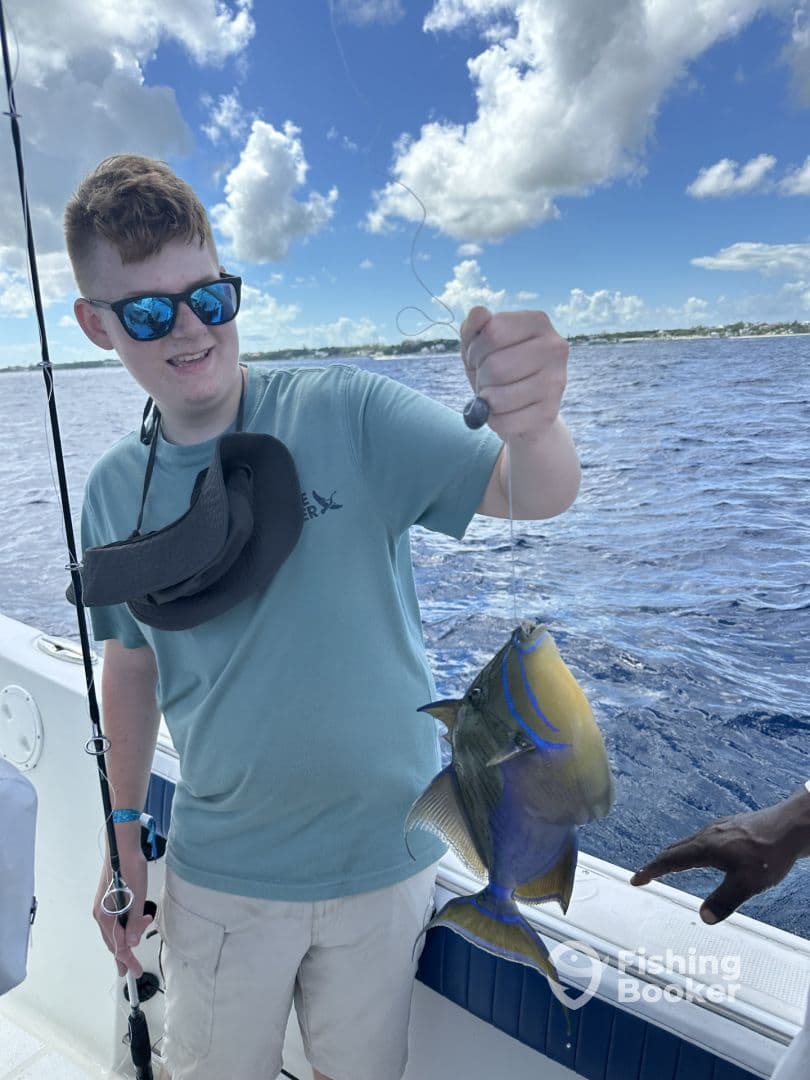 A young angler proudly displaying a colorful fish while fishing on a boat, showcasing a beautiful day on the water.
