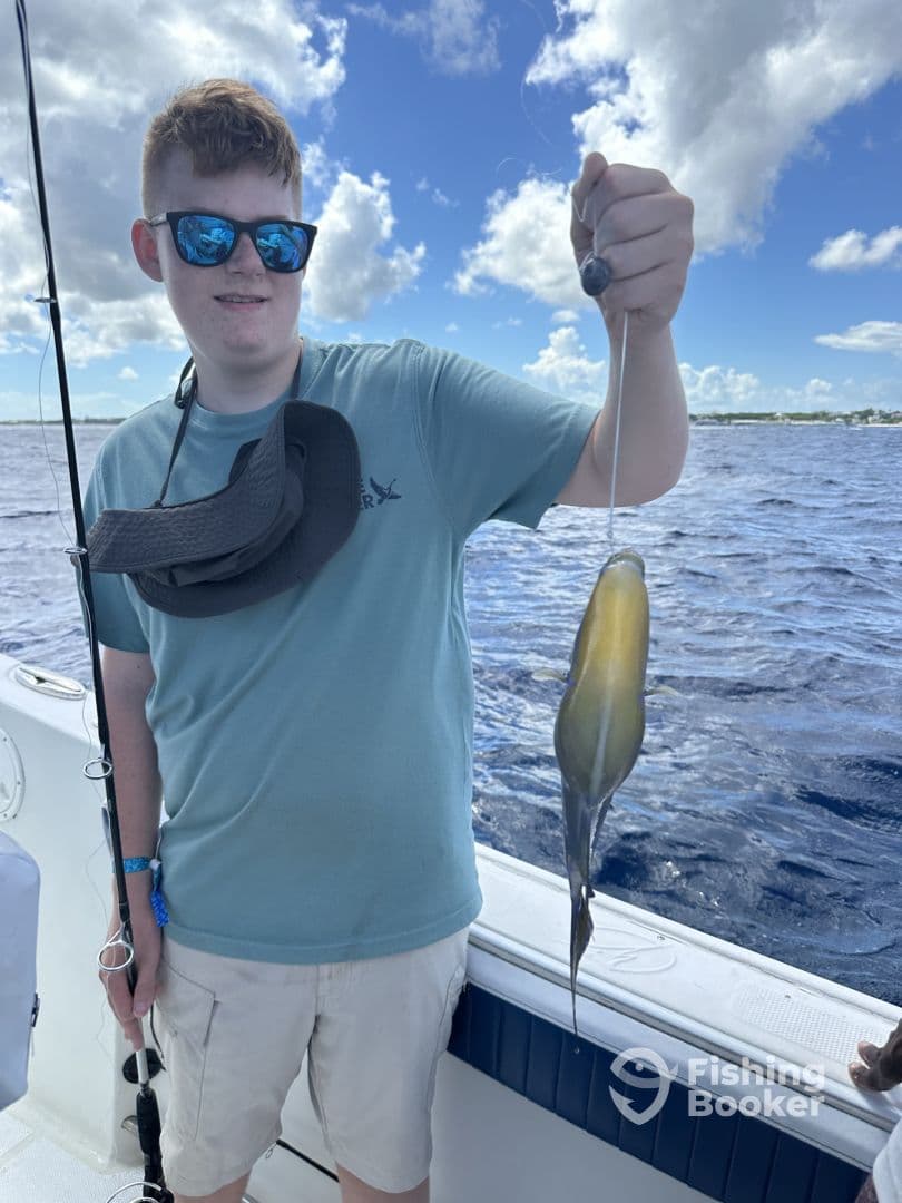 A young angler proudly displaying a squid caught while fishing on a boat, showcasing a sunny day on the water.