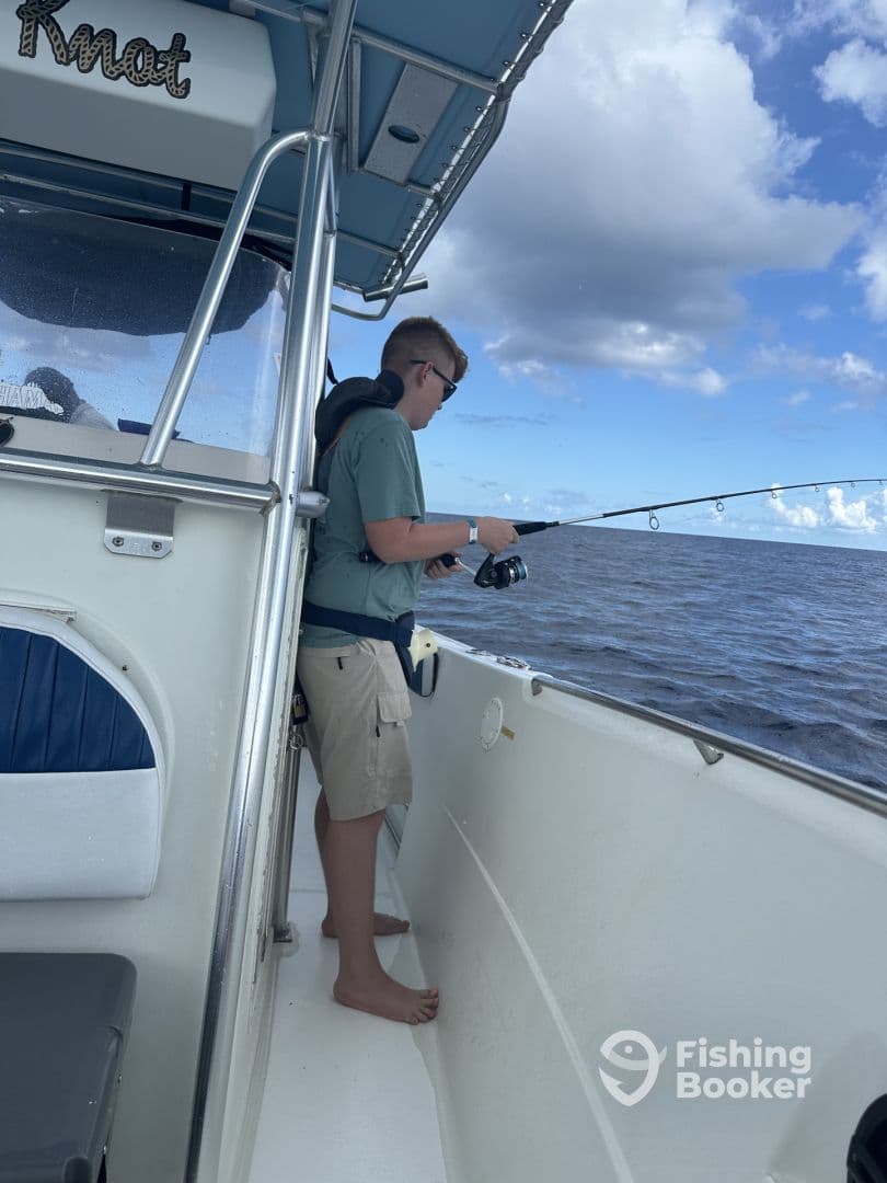 A young angler casting from the side of a boat, enjoying a fishing trip on open waters.