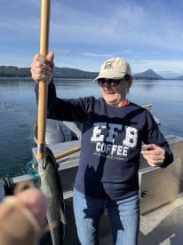 An angler proudly displaying a freshly caught fish while on a scenic fishing trip, surrounded by tranquil waters and mountains.