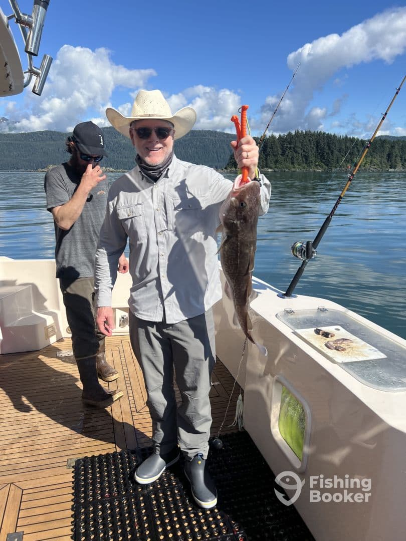 Angler proudly displaying a large Halibut while fishing on a charter boat in a scenic coastal environment.