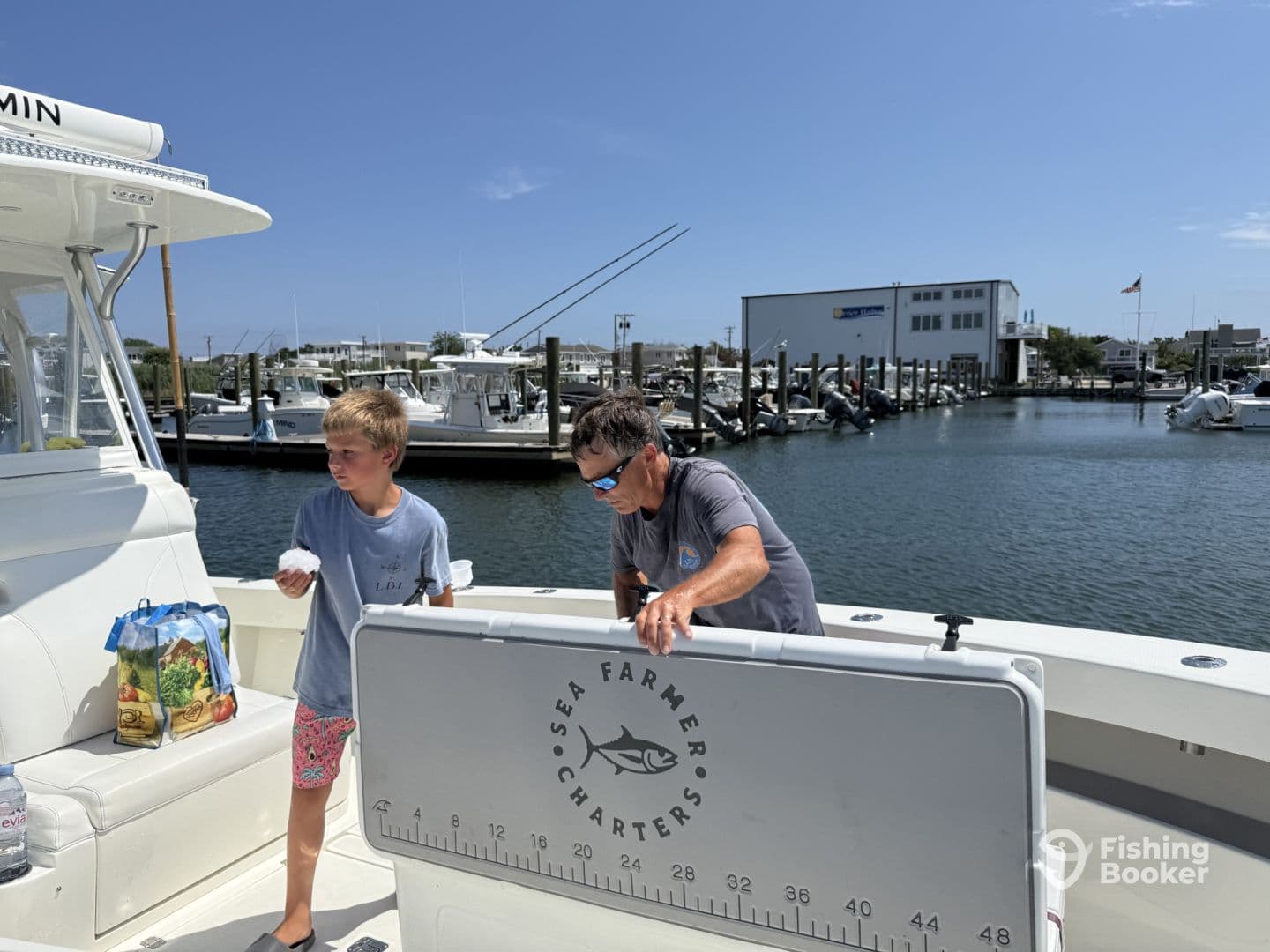 A young boy and an adult are preparing on the boat, showcasing a relaxed atmosphere before heading out for a fishing trip.