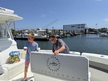 A young boy and an adult are preparing on the boat, showcasing a relaxed atmosphere before heading out for a fishing trip.