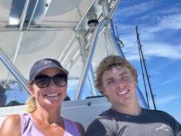 A mother and son enjoying a sunny day aboard a fishing boat, showcasing the comfortable seating and bright blue skies.