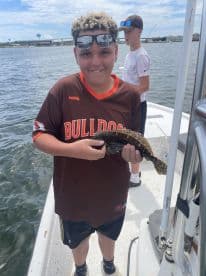 A young angler proudly displaying a caught fish while aboard a fishing boat, enjoying a day on the water.