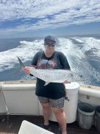 Angler holding a large striped fish while on a boat, showcasing a successful fishing trip in open waters.