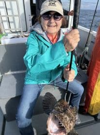 An excited angler proudly displaying a large fish on a fishing charter, showcasing the thrill of deep-sea fishing.
