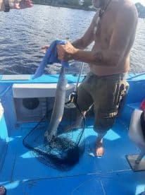 An angler proudly displaying a freshly caught fish aboard a small fishing boat, showcasing the excitement of a successful fishing trip.