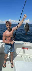 A young angler proudly displaying a caught fish while fishing on a boat in open waters.