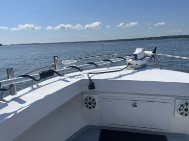 View of the helm area on a fishing boat, showcasing the electronics and layout, with calm waters in the background.