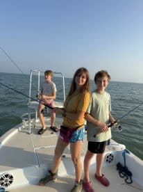 Three young anglers actively fishing on a boat, enjoying a day out on the water.