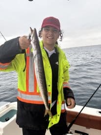 Young angler proudly displaying a caught fish while fishing on a boat, showcasing a vibrant fishing environment.