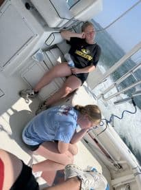 Two young anglers relaxing inside the boat, enjoying a sunny day on the water.