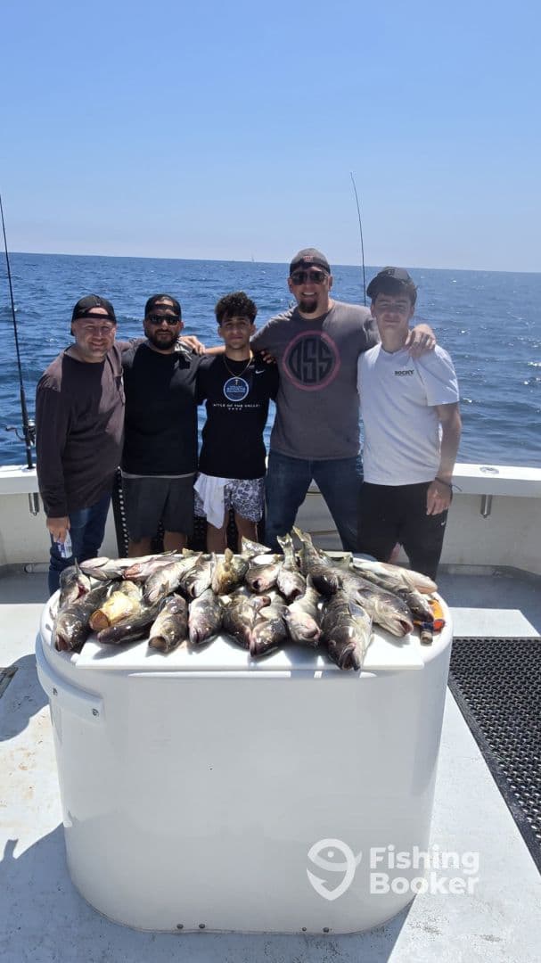 A group of anglers proudly displaying their catch of multiple fish on a fishing charter in open waters.