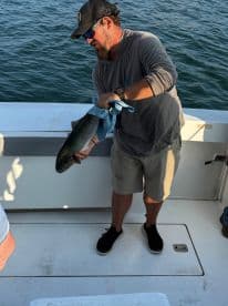 An angler displaying a freshly caught fish on the deck of a fishing boat, showcasing a successful day on the water.