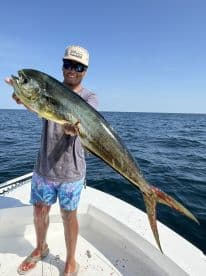 Angler proudly displaying a large Mahi Mahi while fishing offshore, showcasing a successful day on the water.